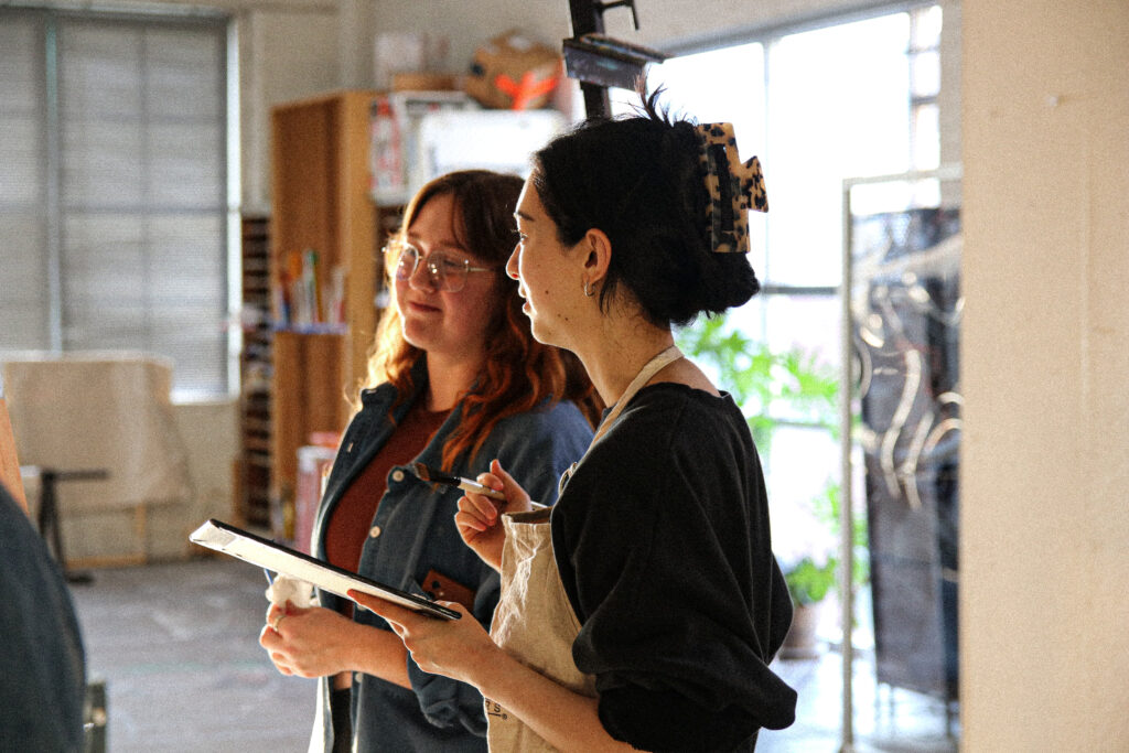 Student receives feedback on their painting from instructor